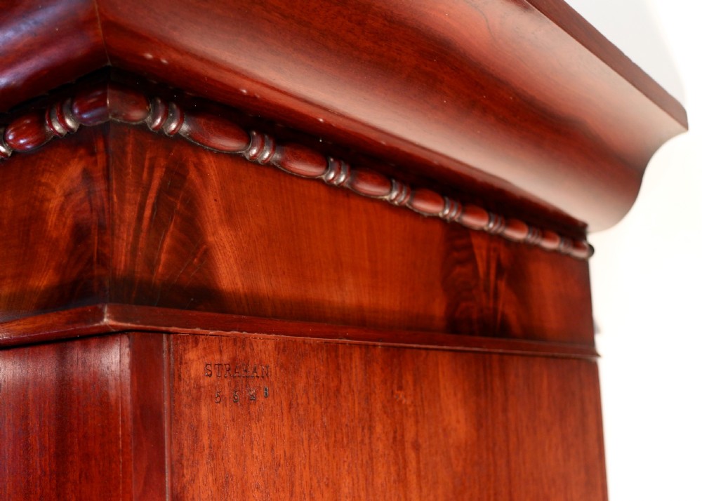 A nineteenth-century breakfront wardrobe featuring flame mahogany veneer, four arched panel doors, and a moulded projecting cornice. View XXVI
