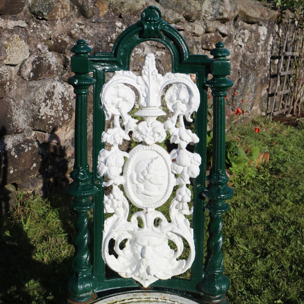 A set of four Victorian cast iron garden chairs featuring white openwork backrests with central medallion cameos framed by dark green structural frames and cabriole legs. View XII