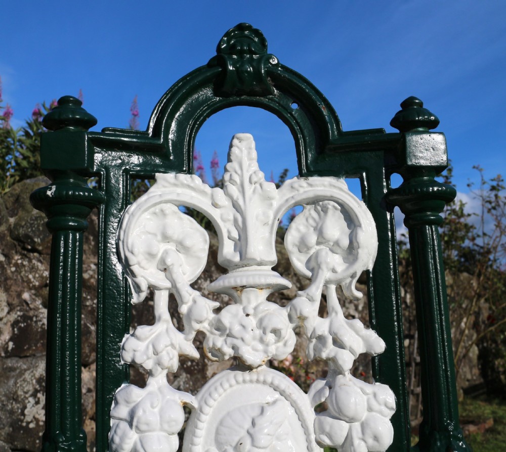 A set of four Victorian cast iron garden chairs featuring white openwork backrests with central medallion cameos framed by dark green structural frames and cabriole legs. View XIII