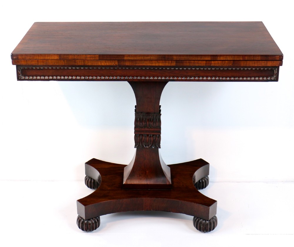 A Regency rosewood tea table featuring a rectangular fold-over top, bead moulding trim, a carved central pedestal, and a quadform base on carved feet. View II