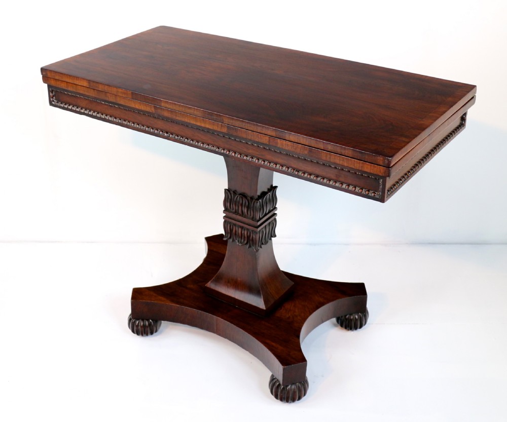 A Regency rosewood tea table featuring a rectangular fold-over top, bead moulding trim, a carved central pedestal, and a quadform base on carved feet. View V