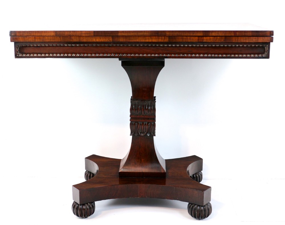 A Regency rosewood tea table featuring a rectangular fold-over top, bead moulding trim, a carved central pedestal, and a quadform base on carved feet. View VI