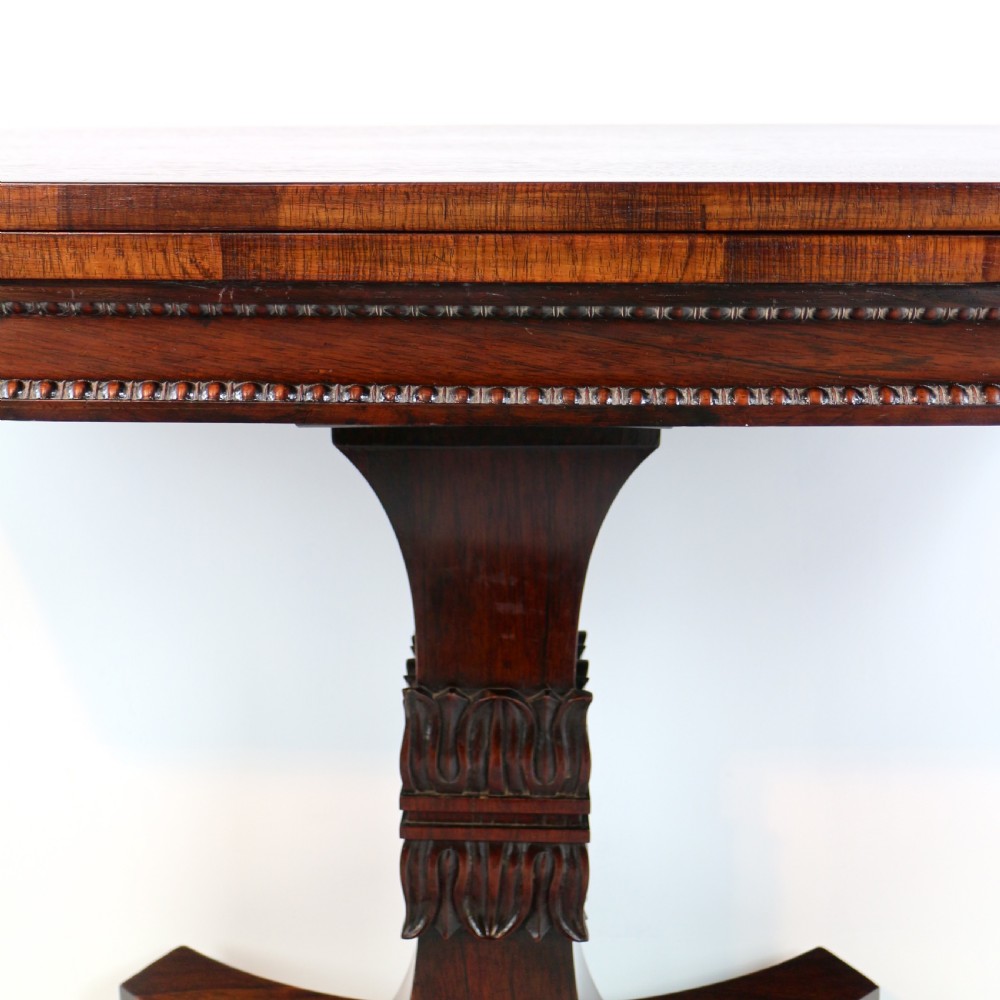 A Regency rosewood tea table featuring a rectangular fold-over top, bead moulding trim, a carved central pedestal, and a quadform base on carved feet. View VIII