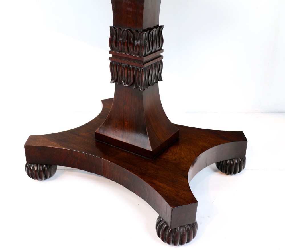 A Regency rosewood tea table featuring a rectangular fold-over top, bead moulding trim, a carved central pedestal, and a quadform base on carved feet. View X