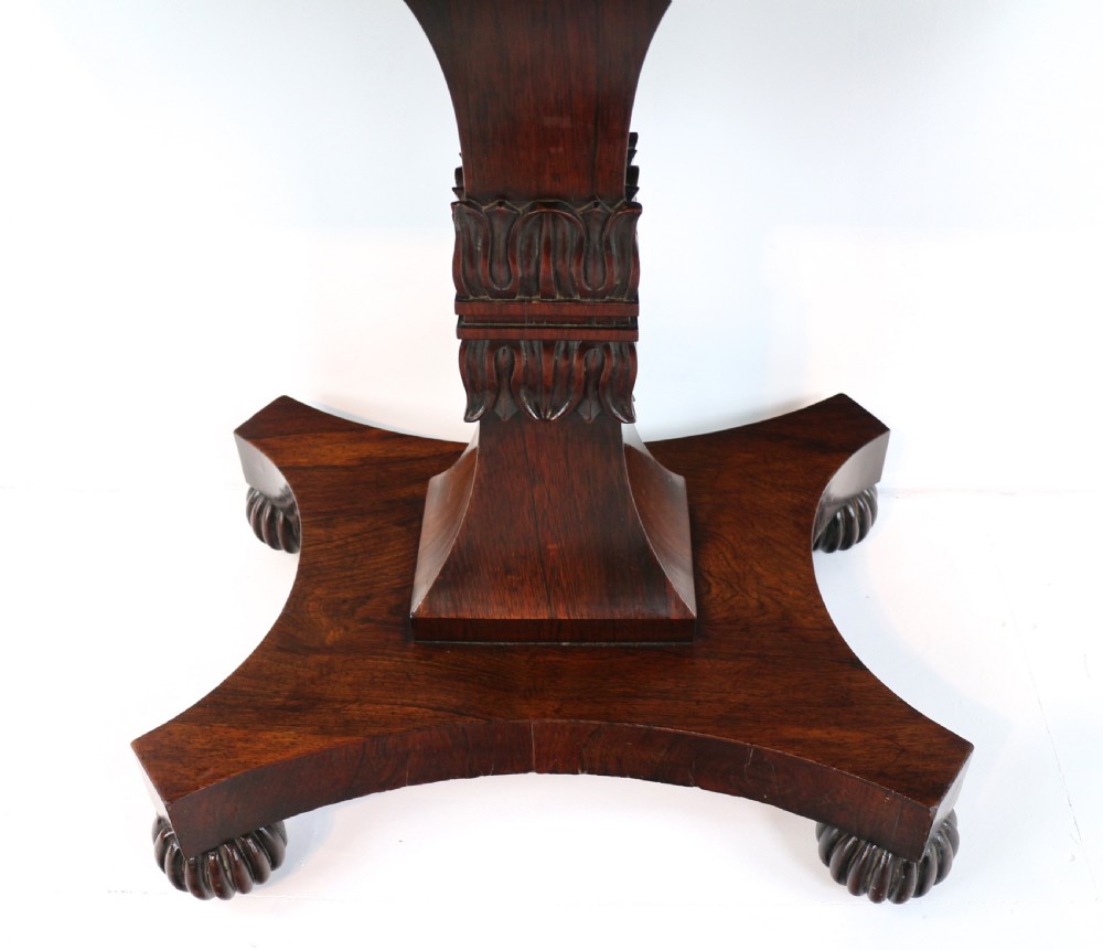 A Regency rosewood tea table featuring a rectangular fold-over top, bead moulding trim, a carved central pedestal, and a quadform base on carved feet. View XI