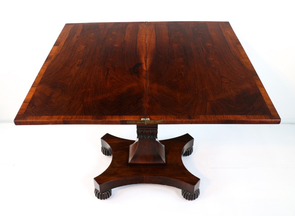 A Regency rosewood tea table featuring a rectangular fold-over top, bead moulding trim, a carved central pedestal, and a quadform base on carved feet. View XV