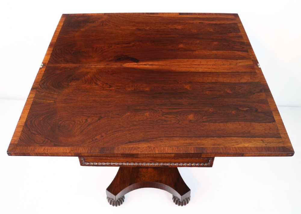 A Regency rosewood tea table featuring a rectangular fold-over top, bead moulding trim, a carved central pedestal, and a quadform base on carved feet. View XVII