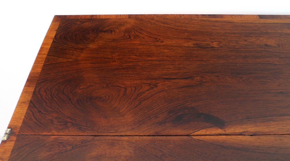 A Regency rosewood tea table featuring a rectangular fold-over top, bead moulding trim, a carved central pedestal, and a quadform base on carved feet. View XX