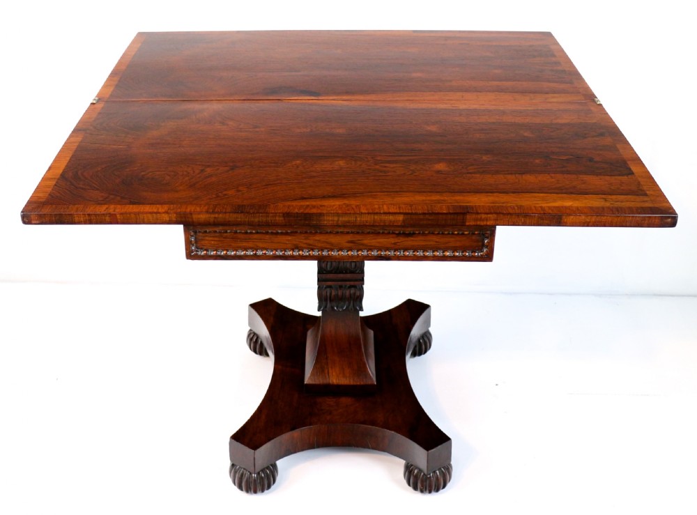 A Regency rosewood tea table featuring a rectangular fold-over top, bead moulding trim, a carved central pedestal, and a quadform base on carved feet. View XXII