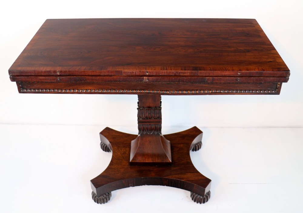 A Regency rosewood tea table featuring a rectangular fold-over top, bead moulding trim, a carved central pedestal, and a quadform base on carved feet. View XXIII