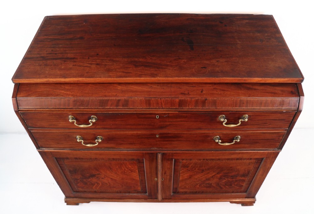 A George III mahogany secretaire low press cupboard featuring flame mahogany veneer panels, brass swan-neck handles, and bracket feet. View VI