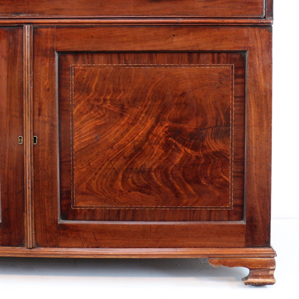 A George III mahogany secretaire low press cupboard featuring flame mahogany veneer panels, brass swan-neck handles, and bracket feet. View IX