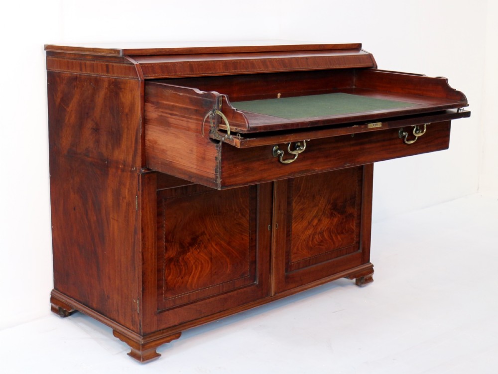 A George III mahogany secretaire low press cupboard featuring flame mahogany veneer panels, brass swan-neck handles, and bracket feet. View XV