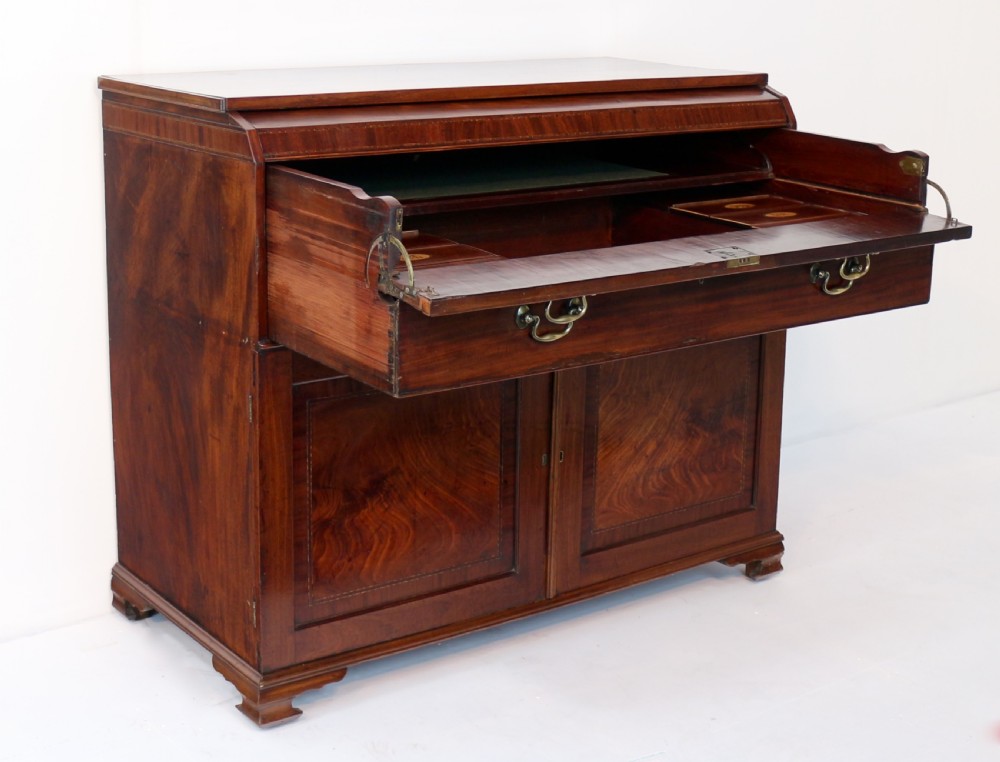 A George III mahogany secretaire low press cupboard featuring flame mahogany veneer panels, brass swan-neck handles, and bracket feet. View XX