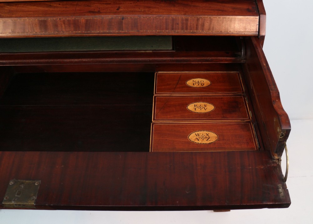 A George III mahogany secretaire low press cupboard featuring flame mahogany veneer panels, brass swan-neck handles, and bracket feet. View XXIV