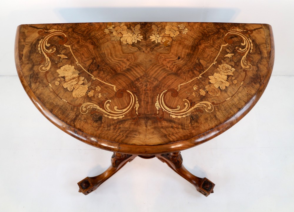 A Victorian burr walnut demilune card table featuring floral marquetry inlays, turned twin-column supports, and a carved central finial on quadruped legs. View XI