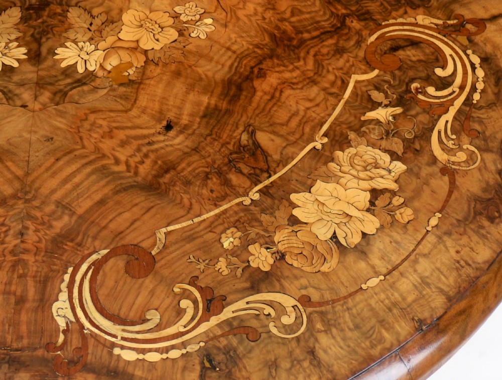 A Victorian burr walnut demilune card table featuring floral marquetry inlays, turned twin-column supports, and a carved central finial on quadruped legs. View XV