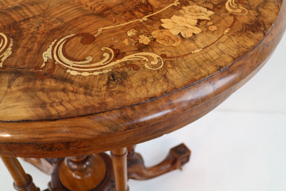 A Victorian burr walnut demilune card table featuring floral marquetry inlays, turned twin-column supports, and a carved central finial on quadruped legs. View XVII