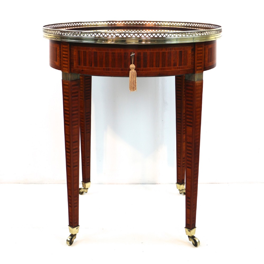 A circular Victorian rosewood bijouterie table featuring a glazed display lid, pierced brass rim gallery, inlaid tapered legs, and brass castors. View III