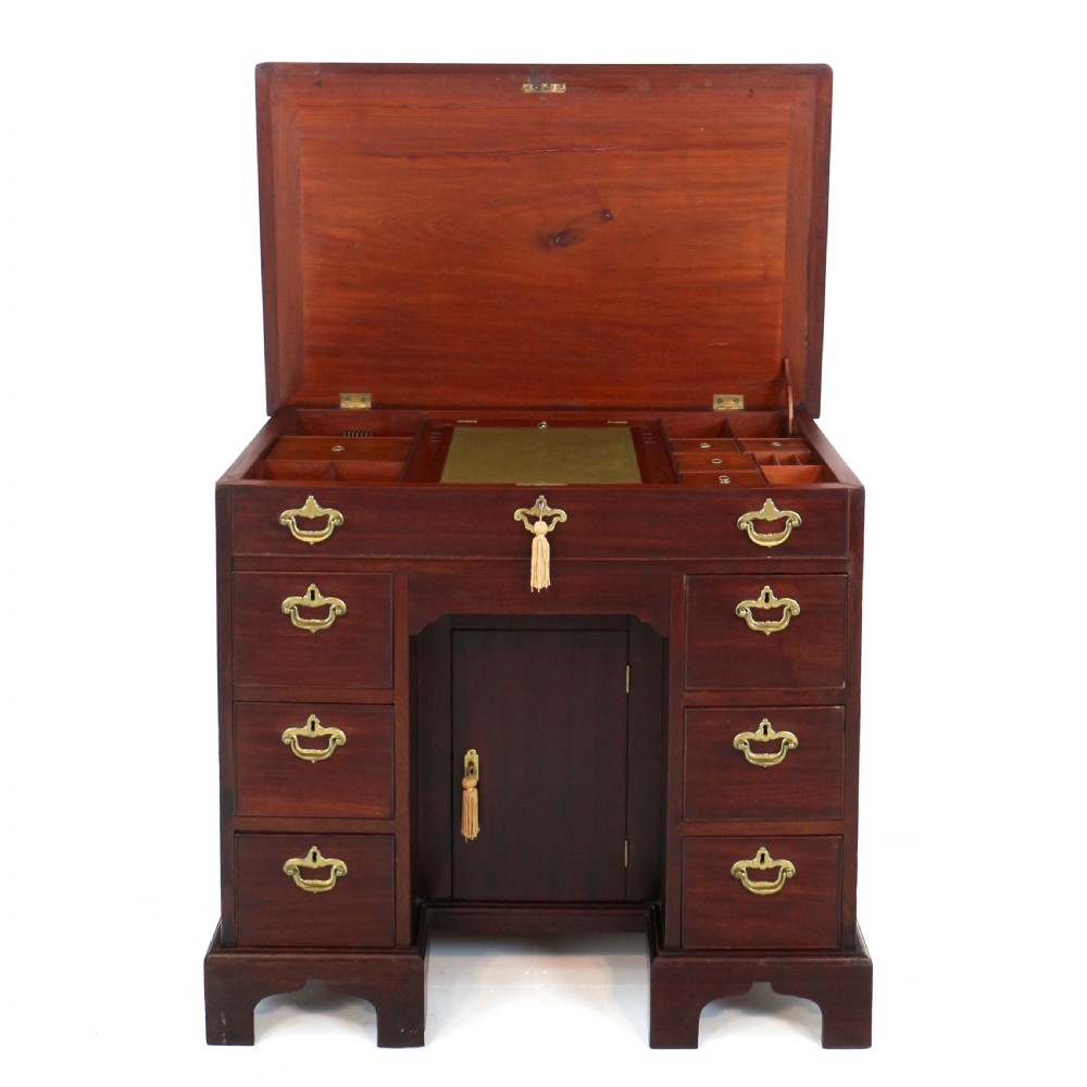 An antique George II red walnut kneehole desk featuring a hinged top that opens to reveal internal compartments and an adjustable green leather mirror, resting on bracket feet with brass handles. View II