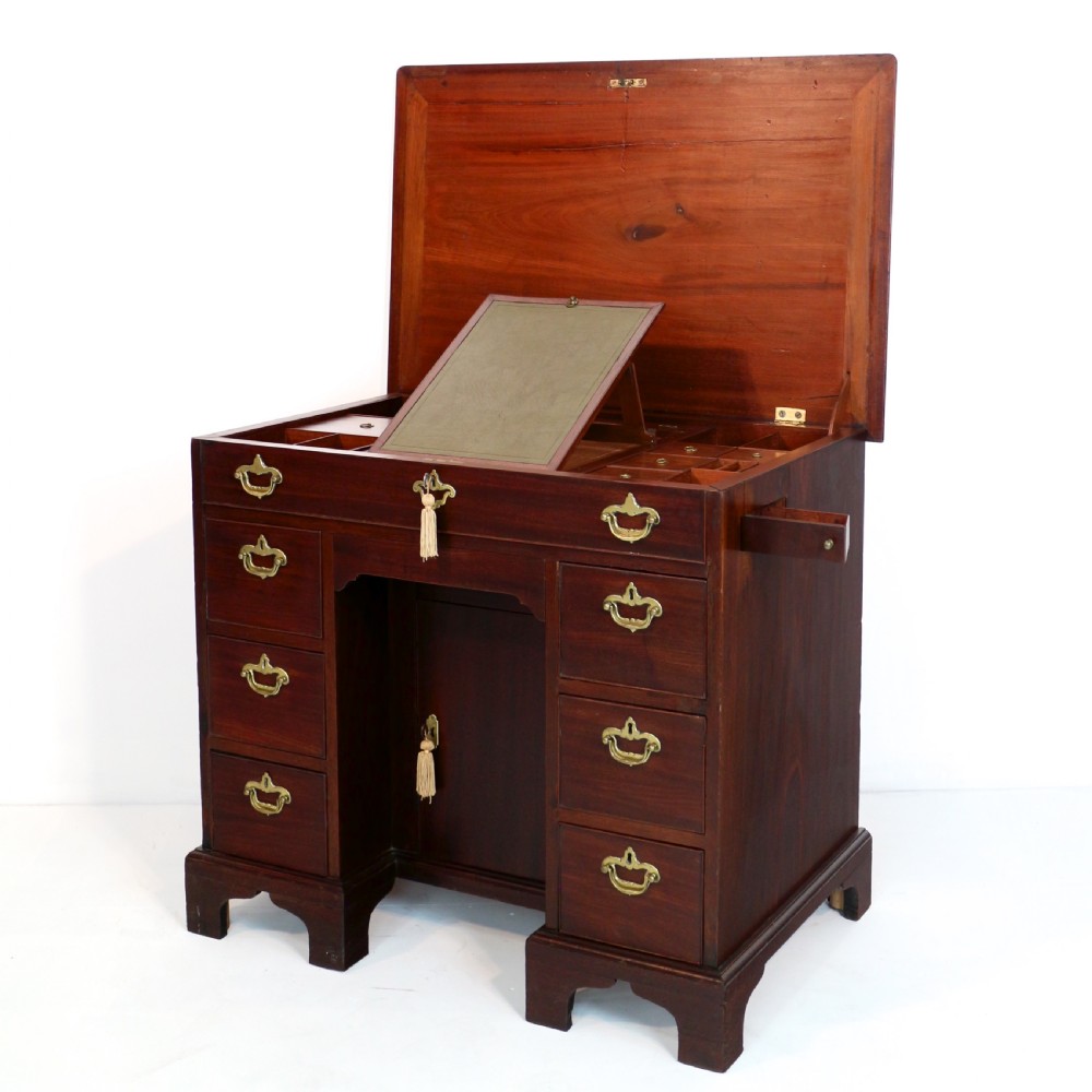An antique George II red walnut kneehole desk featuring a hinged top that opens to reveal internal compartments and an adjustable green leather mirror, resting on bracket feet with brass handles. View VIII