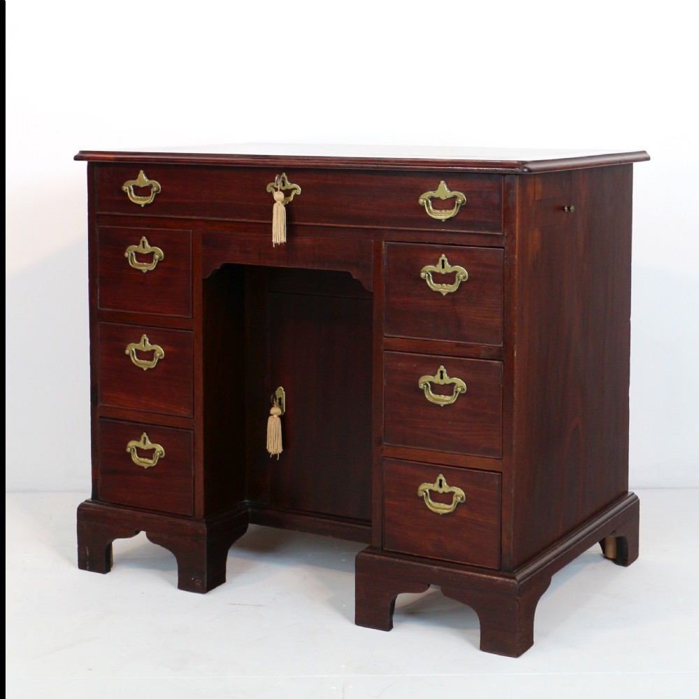 An antique George II red walnut kneehole desk featuring a hinged top that opens to reveal internal compartments and an adjustable green leather mirror, resting on bracket feet with brass handles. View XI