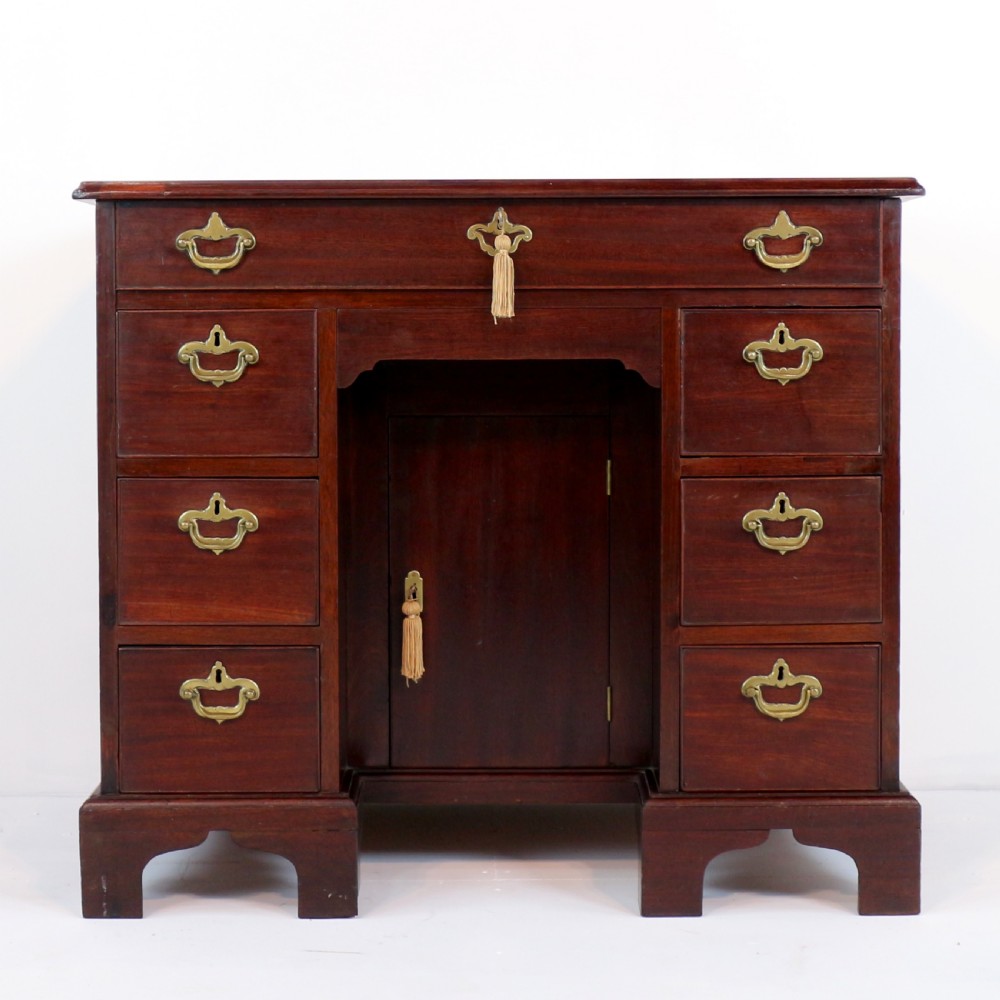 An antique George II red walnut kneehole desk featuring a hinged top that opens to reveal internal compartments and an adjustable green leather mirror, resting on bracket feet with brass handles. View XII