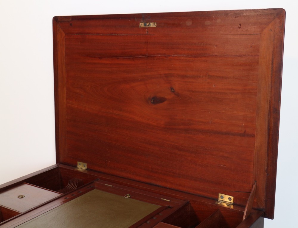 An antique George II red walnut kneehole desk featuring a hinged top that opens to reveal internal compartments and an adjustable green leather mirror, resting on bracket feet with brass handles. View XXII