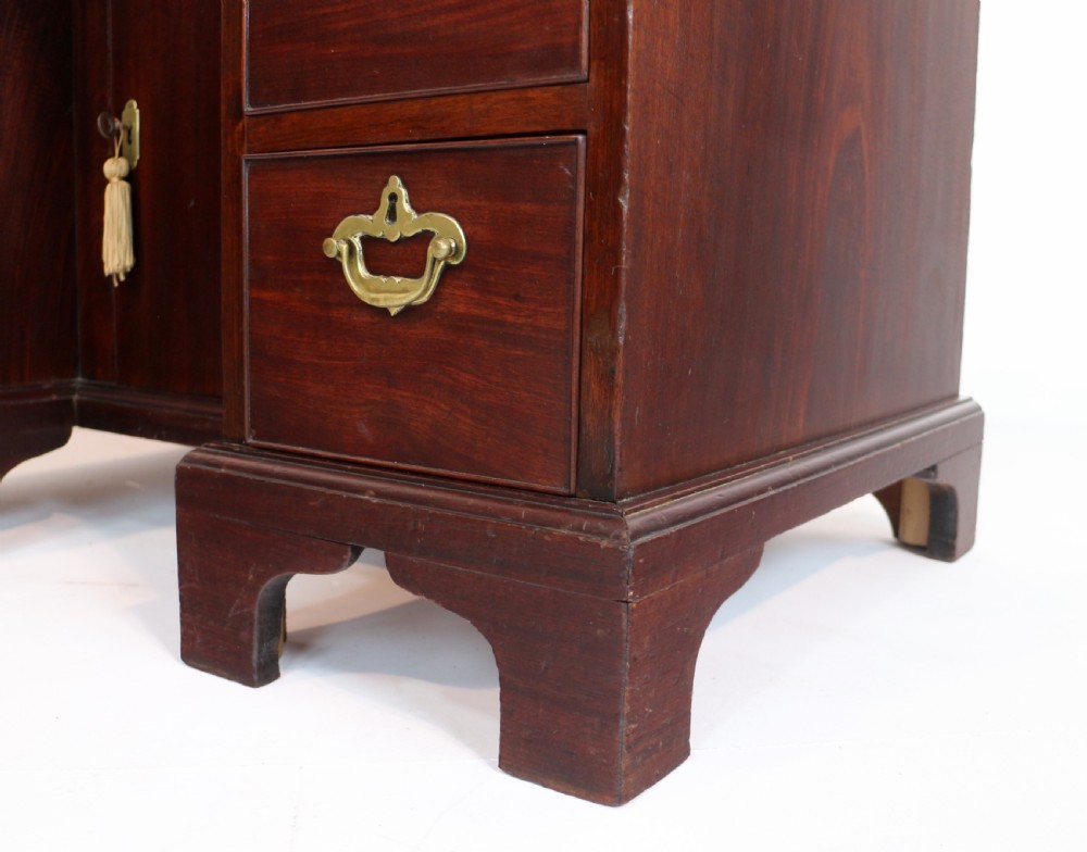 An antique George II red walnut kneehole desk featuring a hinged top that opens to reveal internal compartments and an adjustable green leather mirror, resting on bracket feet with brass handles. View XXVIII