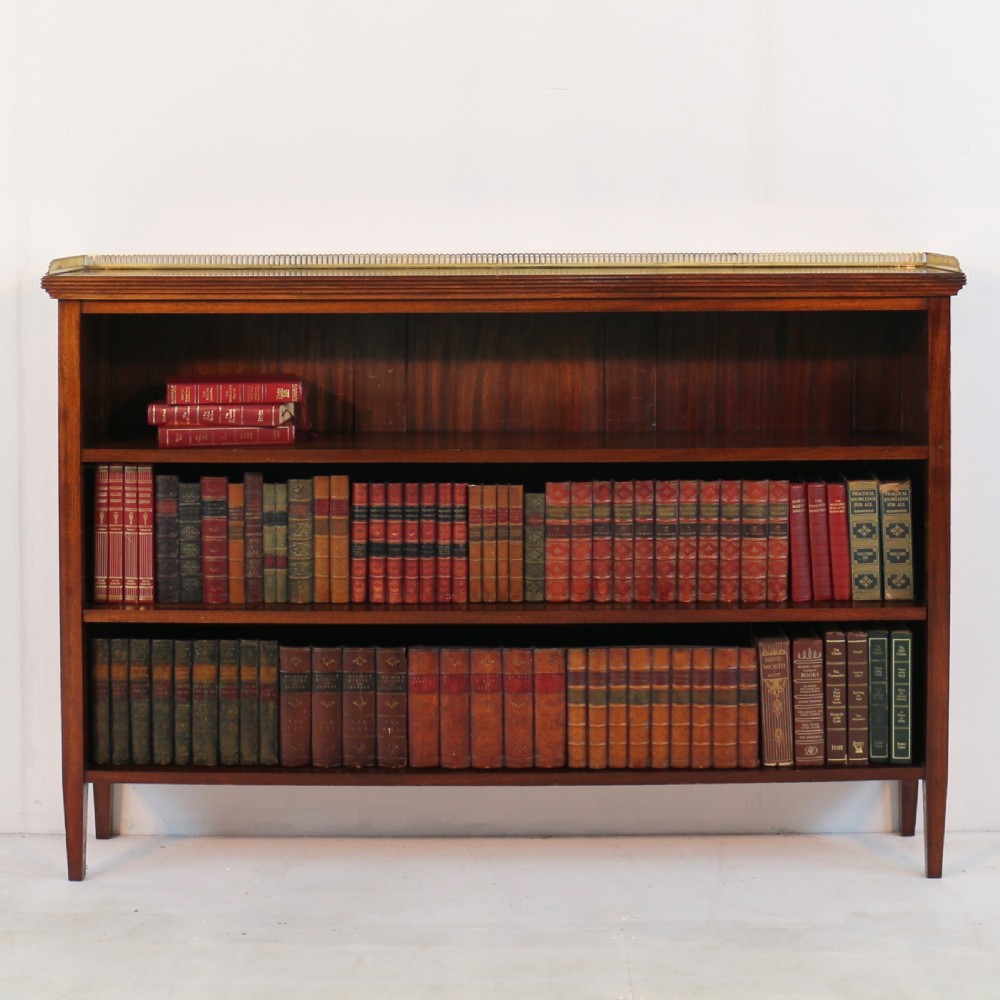 A Victorian walnut open bookcase featuring three horizontal shelves and a decorative brass gallery rail along the top edge. View VI