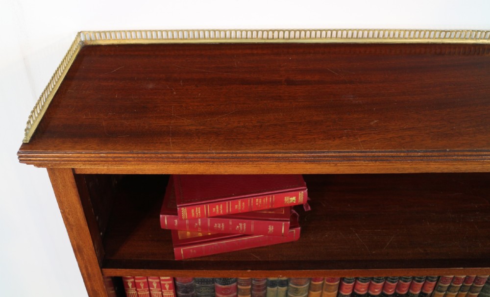 A Victorian walnut open bookcase featuring three horizontal shelves and a decorative brass gallery rail along the top edge. View VII
