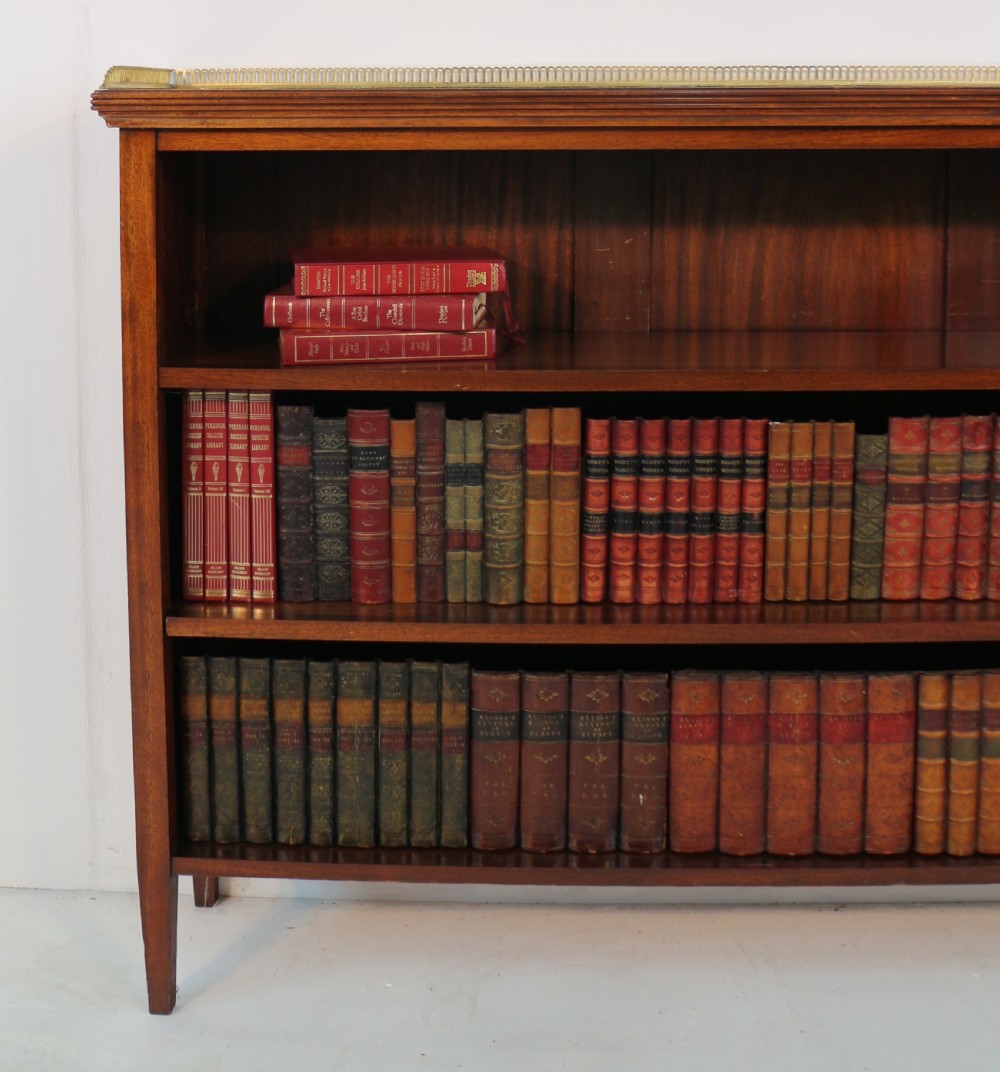 A Victorian walnut open bookcase featuring three horizontal shelves and a decorative brass gallery rail along the top edge. View VIII