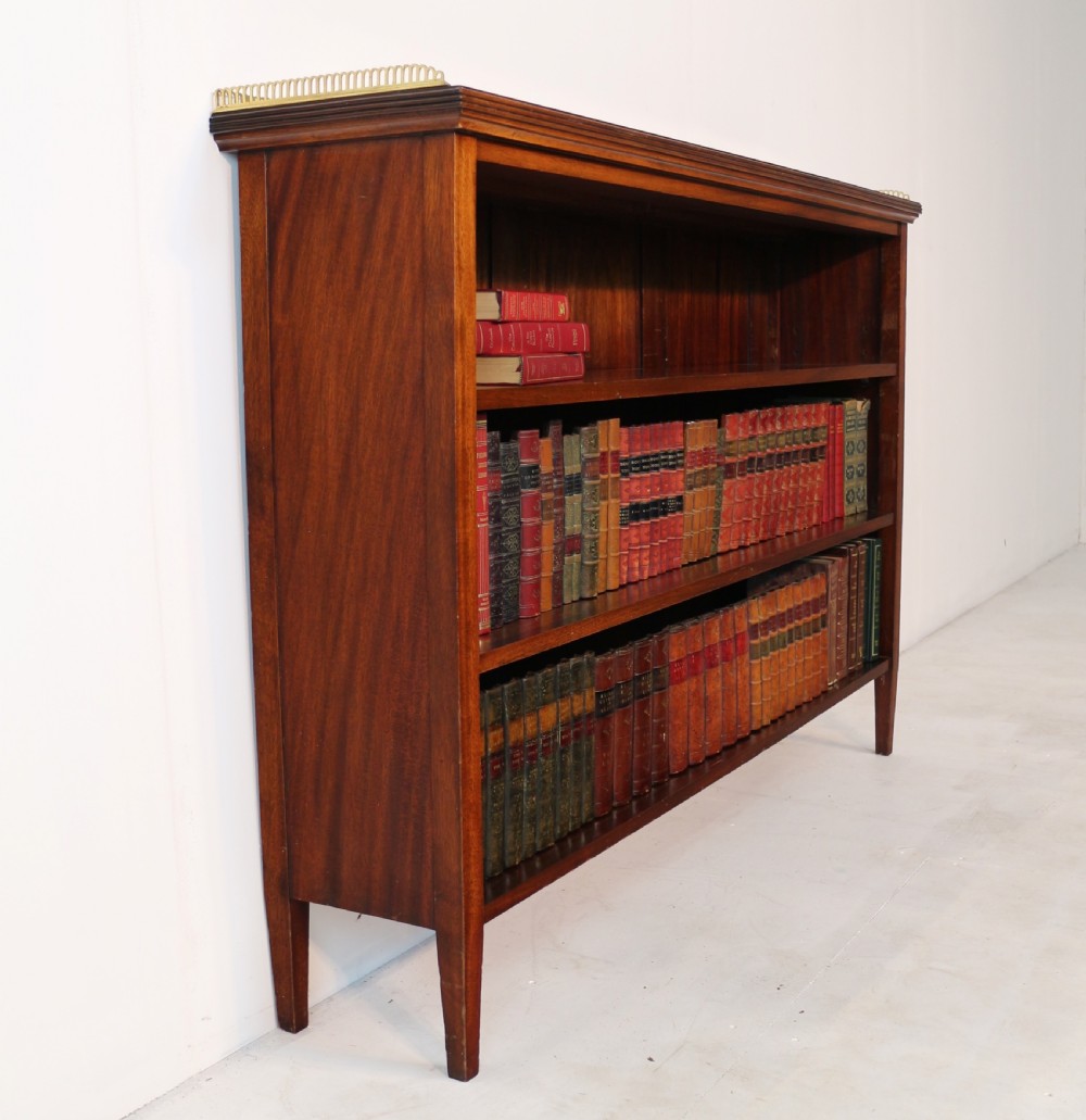 A Victorian walnut open bookcase featuring three horizontal shelves and a decorative brass gallery rail along the top edge. View XVI