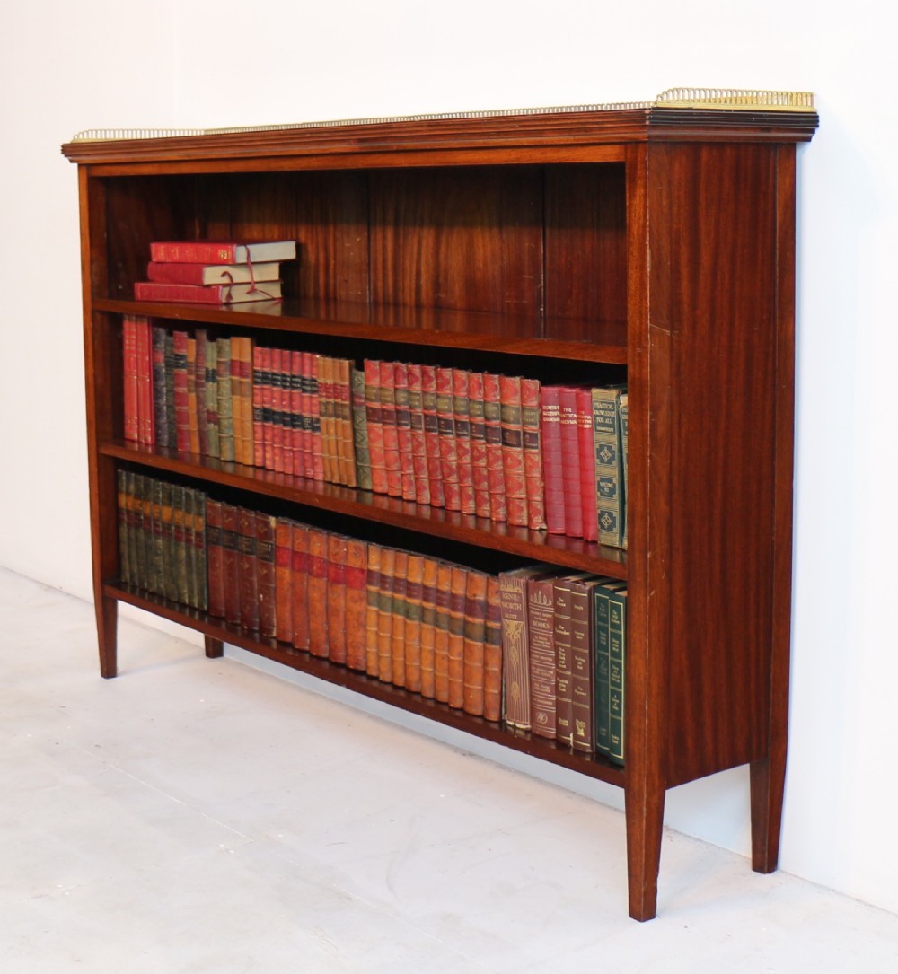 A Victorian walnut open bookcase featuring three horizontal shelves and a decorative brass gallery rail along the top edge. View XIX