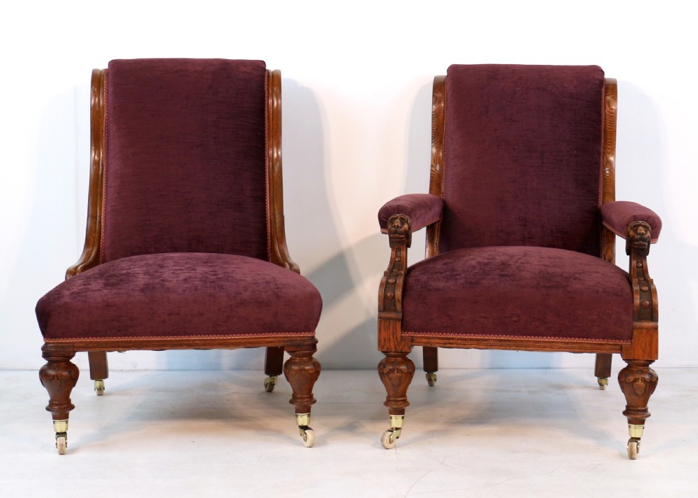 A pair of Victorian oak library chairs upholstered in plum velvet featuring carved lion head arm terminals and brass castors. View III