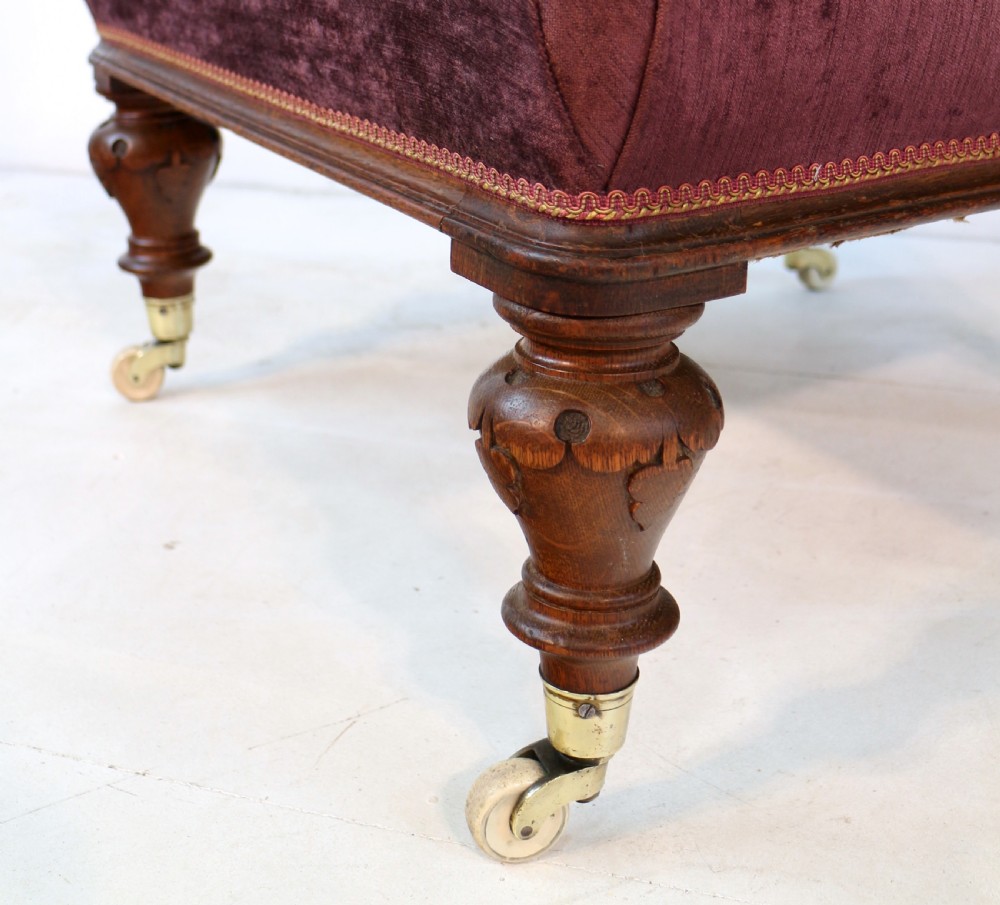 A pair of Victorian oak library chairs upholstered in plum velvet featuring carved lion head arm terminals and brass castors. View XIII