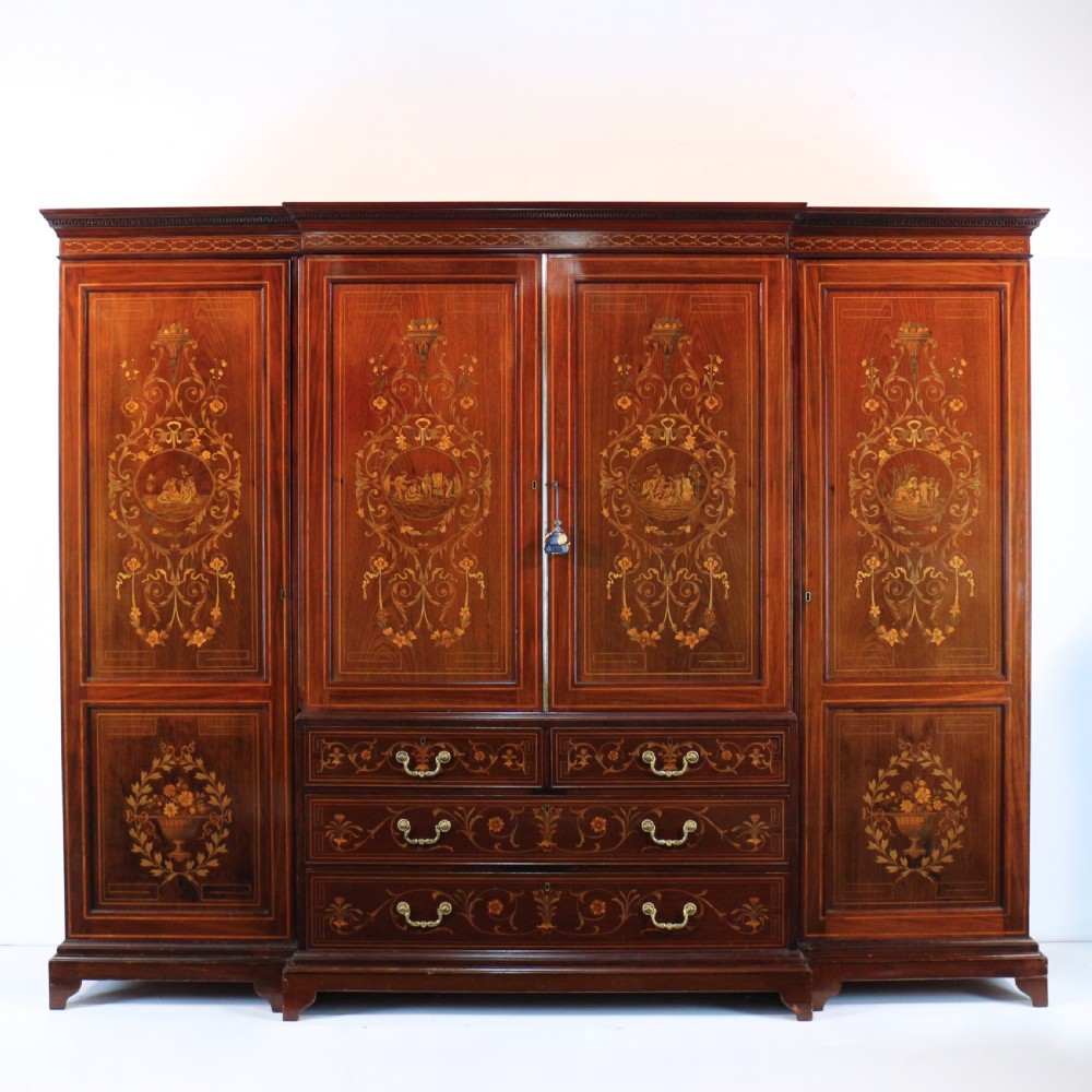 A large Victorian mahogany breakfront wardrobe with intricate floral marquetry inlays on the panel doors and lower drawer fronts.