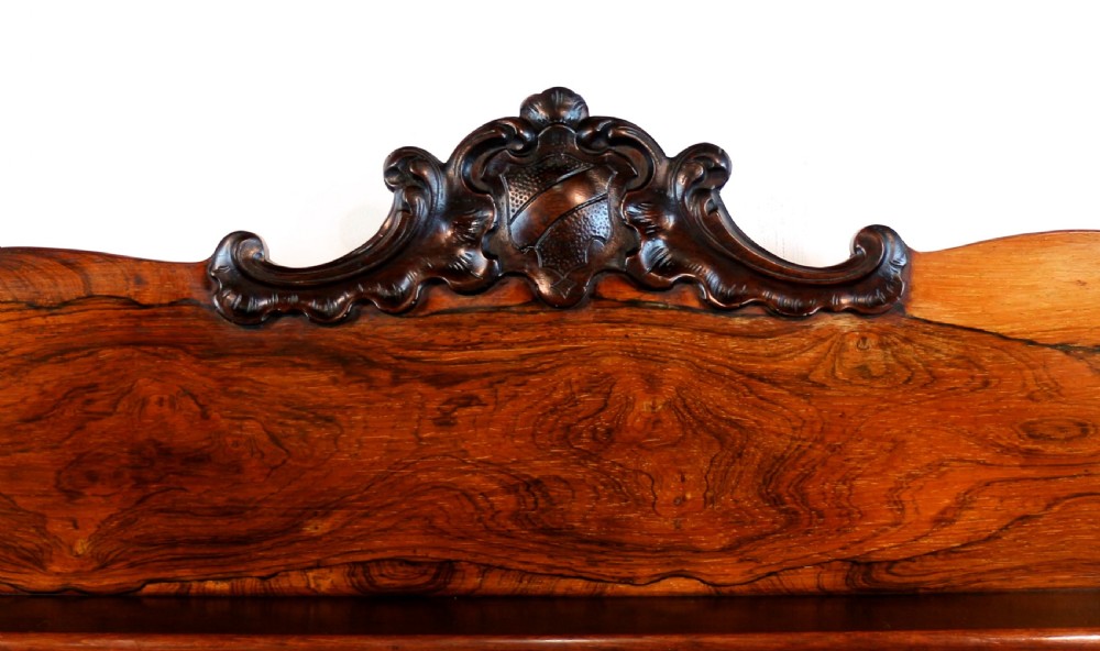 A Regency period rosewood waterfall bookcase with graduated open shelves, carved scroll sides, lower drawers, and turned feet. View V