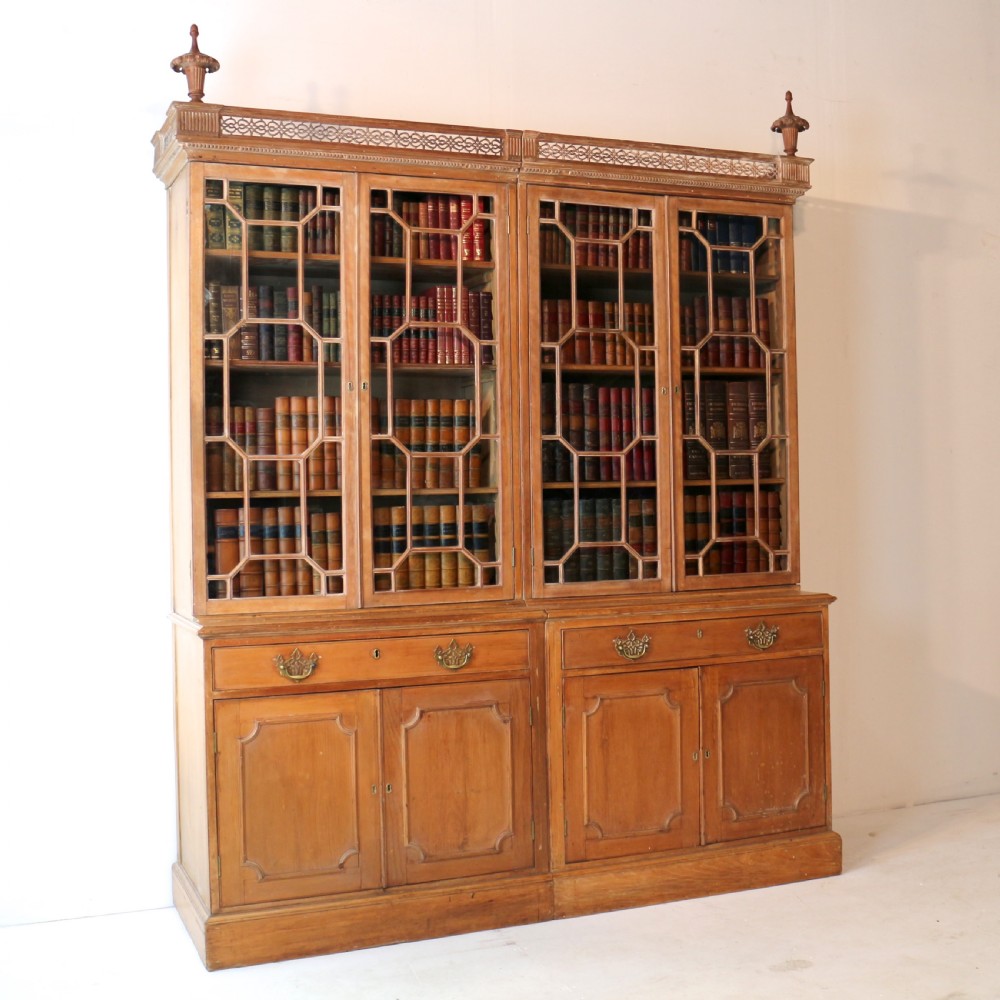 A large George III Chippendale period double bookcase crafted in natural pine, featuring astragal glazed upper doors topped with urn finials and lower panelled cupboards. View V
