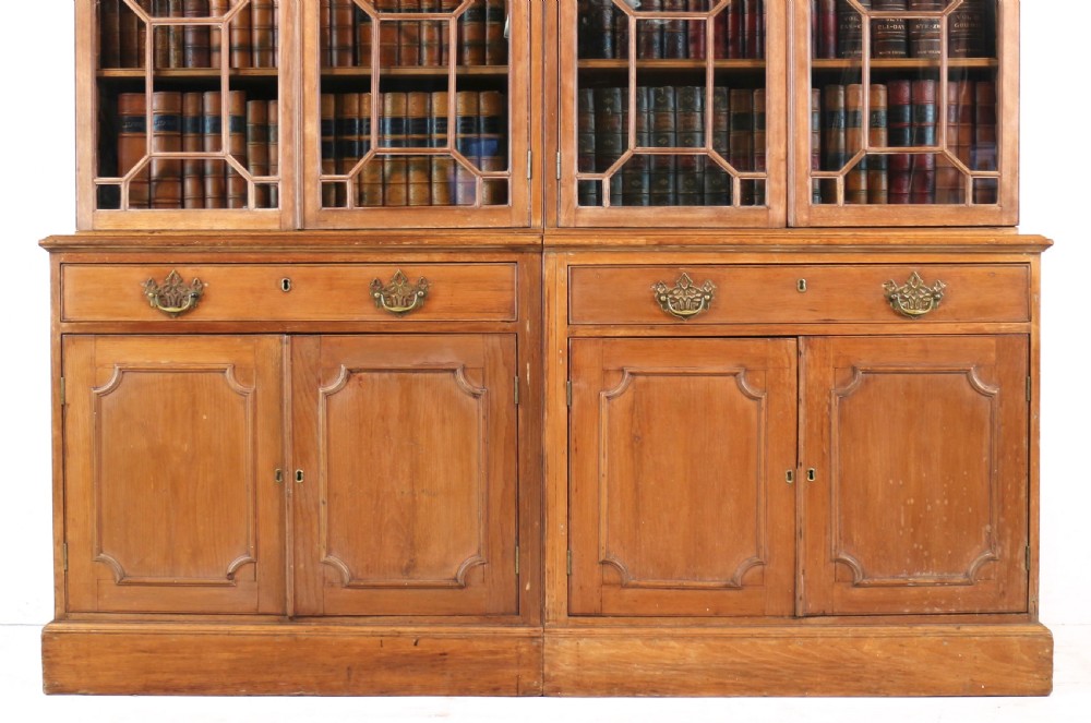 A large George III Chippendale period double bookcase crafted in natural pine, featuring astragal glazed upper doors topped with urn finials and lower panelled cupboards. View VI