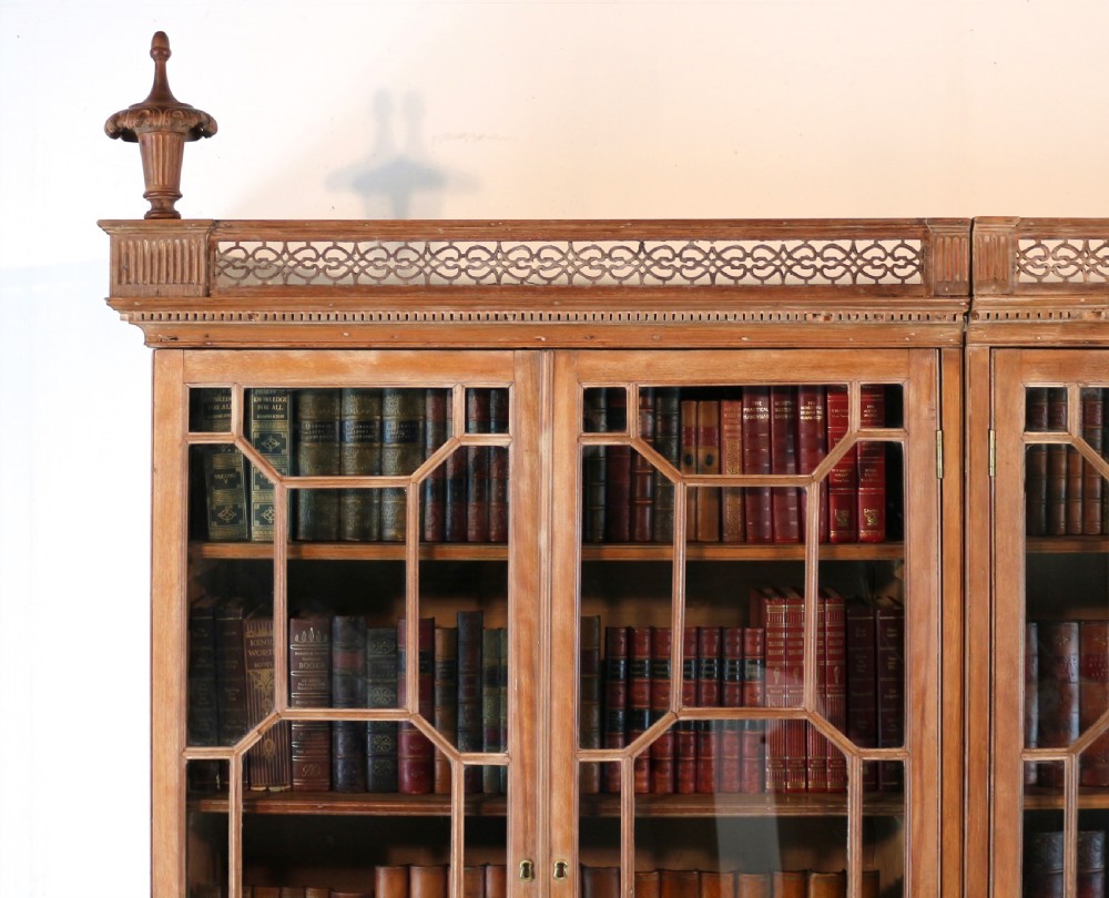 A large George III Chippendale period double bookcase crafted in natural pine, featuring astragal glazed upper doors topped with urn finials and lower panelled cupboards. View VII