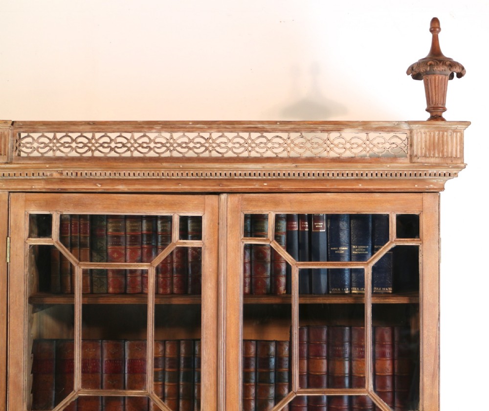 A large George III Chippendale period double bookcase crafted in natural pine, featuring astragal glazed upper doors topped with urn finials and lower panelled cupboards. View VIII