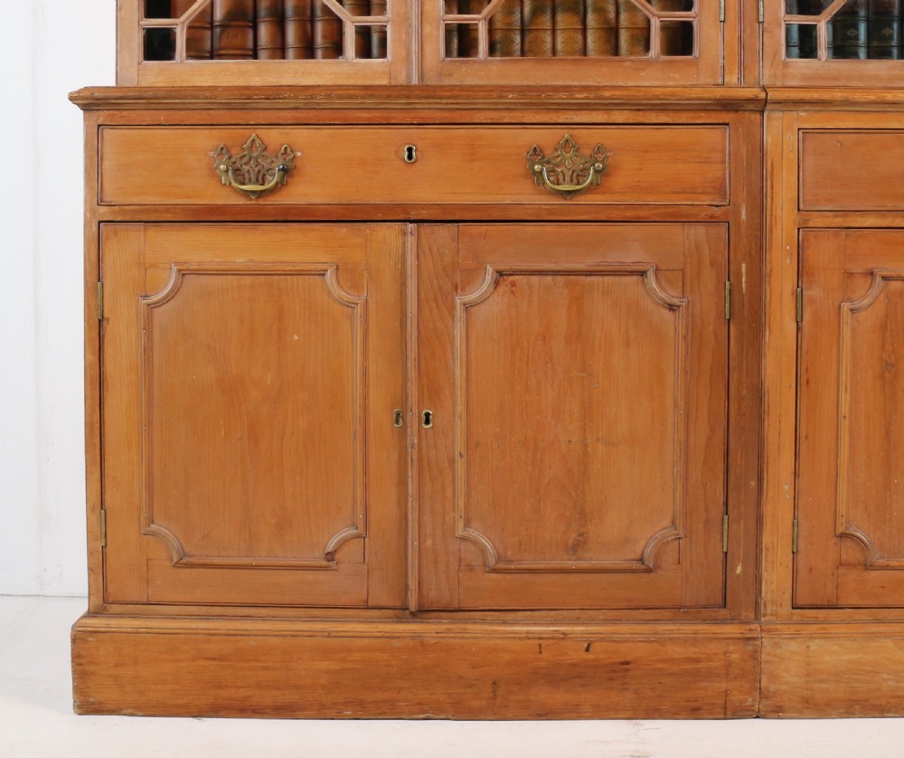 A large George III Chippendale period double bookcase crafted in natural pine, featuring astragal glazed upper doors topped with urn finials and lower panelled cupboards. View IX