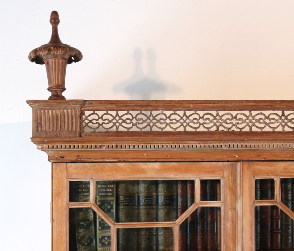 A large George III Chippendale period double bookcase crafted in natural pine, featuring astragal glazed upper doors topped with urn finials and lower panelled cupboards. View XII