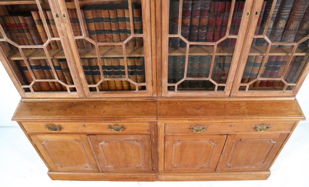 A large George III Chippendale period double bookcase crafted in natural pine, featuring astragal glazed upper doors topped with urn finials and lower panelled cupboards. View XVII
