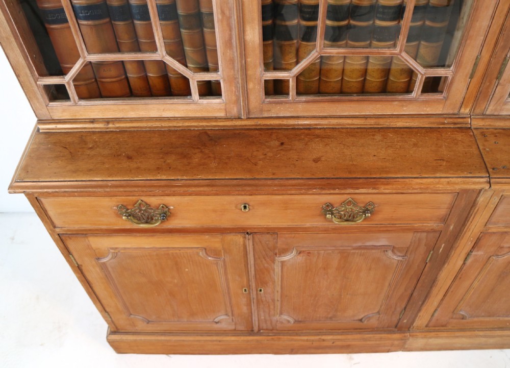 A large George III Chippendale period double bookcase crafted in natural pine, featuring astragal glazed upper doors topped with urn finials and lower panelled cupboards. View XVIII