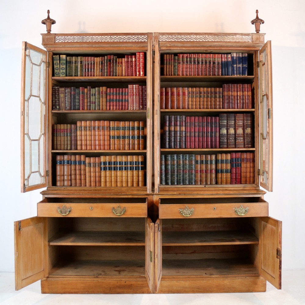A large George III Chippendale period double bookcase crafted in natural pine, featuring astragal glazed upper doors topped with urn finials and lower panelled cupboards. View XX