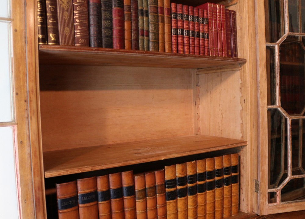 A large George III Chippendale period double bookcase crafted in natural pine, featuring astragal glazed upper doors topped with urn finials and lower panelled cupboards. View XXIII