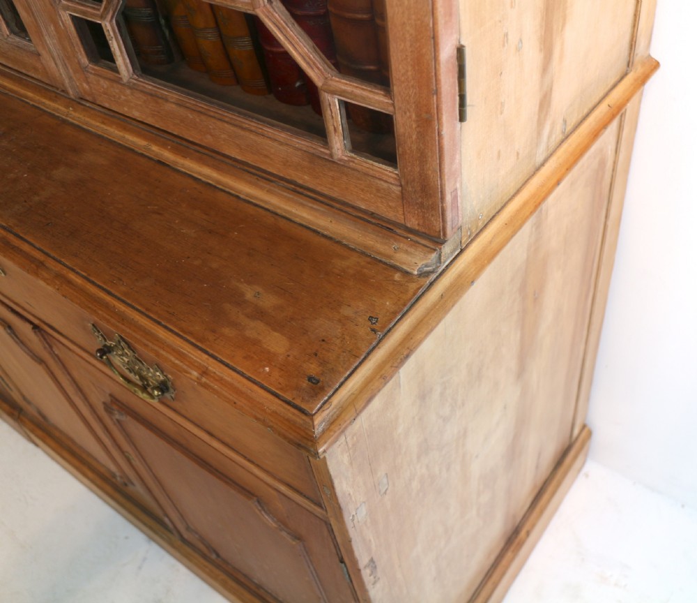 A large George III Chippendale period double bookcase crafted in natural pine, featuring astragal glazed upper doors topped with urn finials and lower panelled cupboards. View XXV