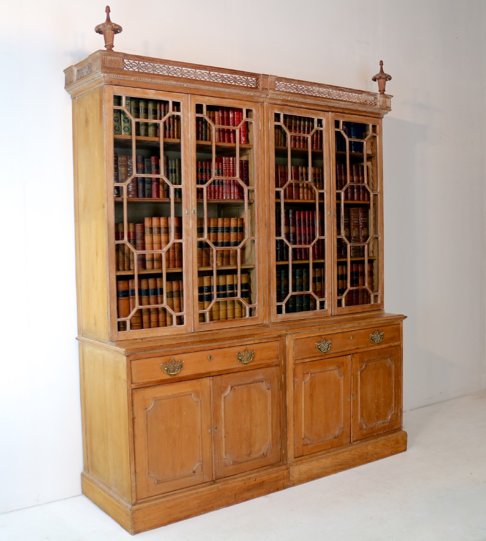A large George III Chippendale period double bookcase crafted in natural pine, featuring astragal glazed upper doors topped with urn finials and lower panelled cupboards. View XXVI
